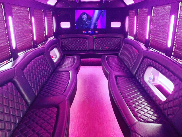 Party bus interior with pink LED lighting and leather seating