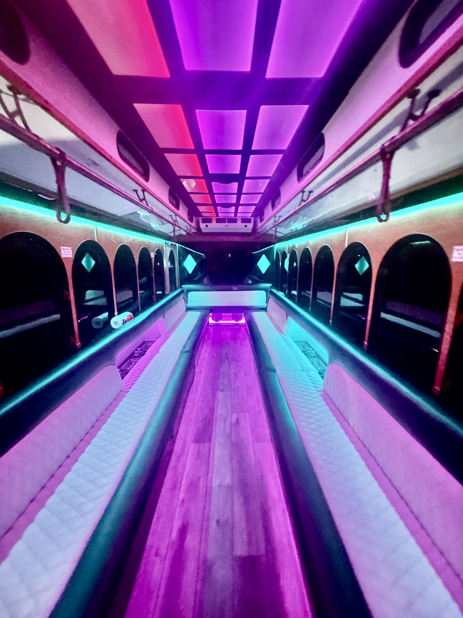 Trolley limo interior with pink and teal LED lighting and white leather seating
